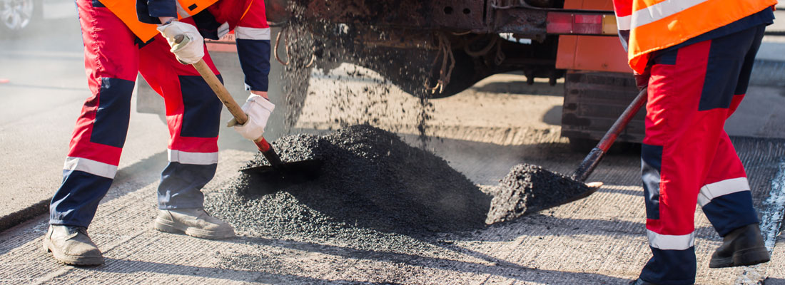 Two men spreading hot asphalt in Tampa on an asphalt road.